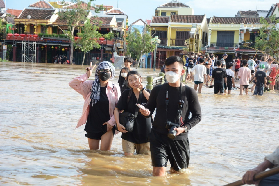 Khách du lịch trải nghiệm cảnh ngập lụt ở phố cổ Hội An. (Ảnh: Văn Dũng/TTXVN)