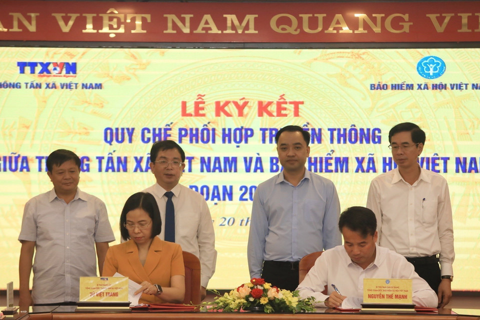 Tổng Giám đốc Thông tấn xã Việt Nam Vũ Việt Trang và Tổng Giám đốc Bảo hiểm xã hội Việt Nam Nguyễn Thế Mạnh trao đổi biên bản ký kết hợp tác tại buổi lễ. (Ảnh: Tuấn Anh/TTXVN)