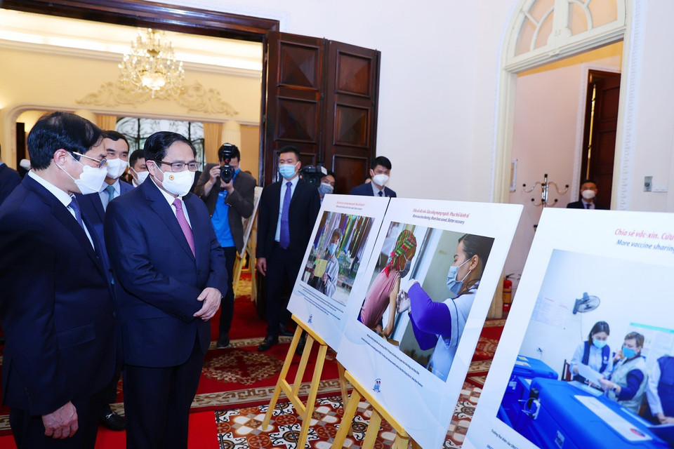 Thủ tướng Phạm Minh Chính tham quan trưng bày ảnh về hoạt động đối ngoại vaccine phòng, chống dịch COVID-19. (Ảnh: Dương Giang/TTXVN)