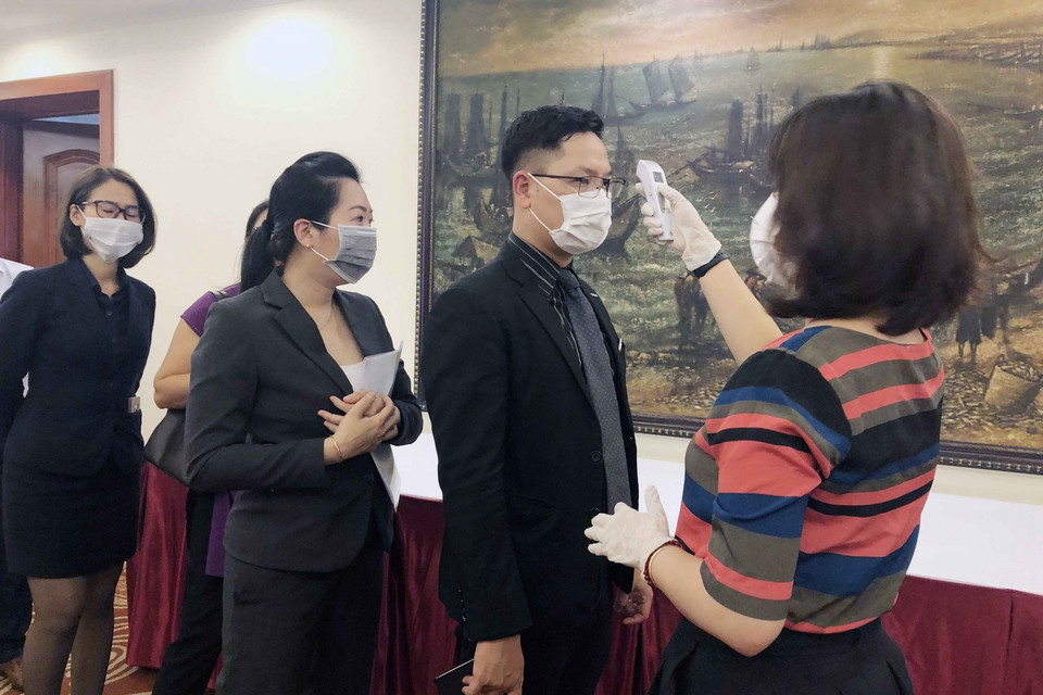 Khách đến dự hội nghị ở TP Hồ Chí Minh được kiểm tra nhiệt độ, rửa tay bằng nước diệt khẩu và phát khẩu trang miễn phí. (Ảnh: Mỹ Phương/TTXVN)