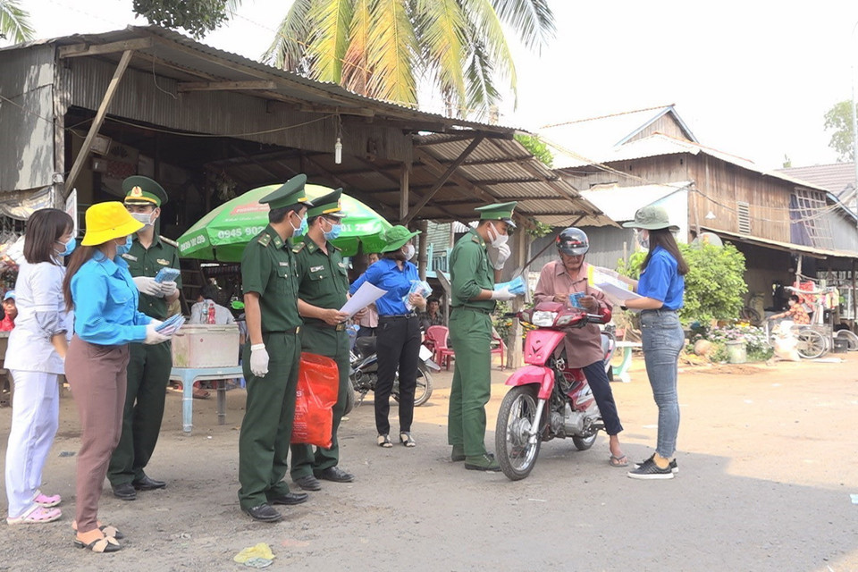 Bộ đội biên phòng Cửa khẩu Quốc tế Thường Phước (Đồng Tháp) cùng Đoàn viên thanh niên phát khẩu trang y tế miễn phí và hỗ trợ người dân những thông tin về diễn biến dịch bệnh. (Ảnh: Chương Đài/TTXVN)