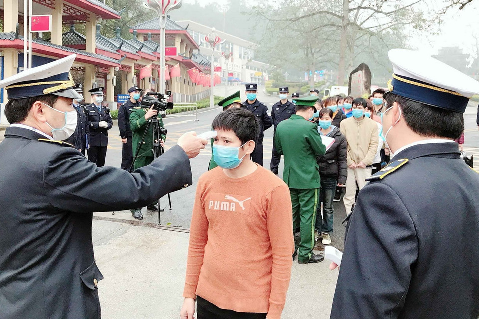 Nhân viên Trung tâm Kiểm dịch Y tế Quốc tế tại Cửa khẩu Quốc tế Hữu Nghị (Lạng Sơn) tiến hành đo thân nhiệt những người nhập cảnh ngay tại biên giới trước khi làm thủ tục nhập cảnh vào Việt Nam. (Ảnh: Thái Thuần/TTXVN)