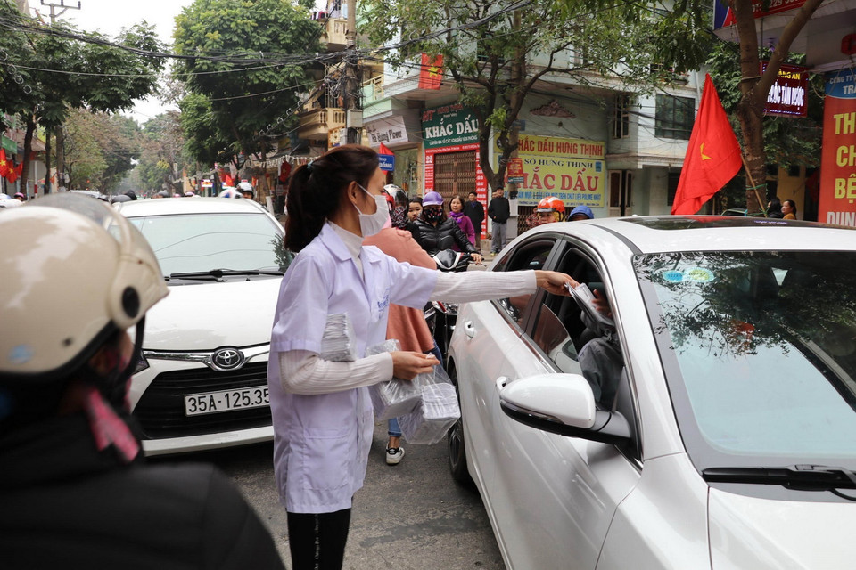 Nhân viên một cửa hàng tân dược ở thành phố Ninh Bình phát khẩu trang y tế miễn phí cho người dân. (Ảnh: Đức Phương/TTXVN)