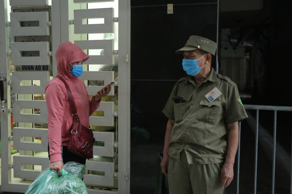 Người dân gọi điện cho người thân trong khu vực phong tỏa ra lấy nhu yếu phẩm. (Ảnh: Hoàng Hiếu/TTXVN)