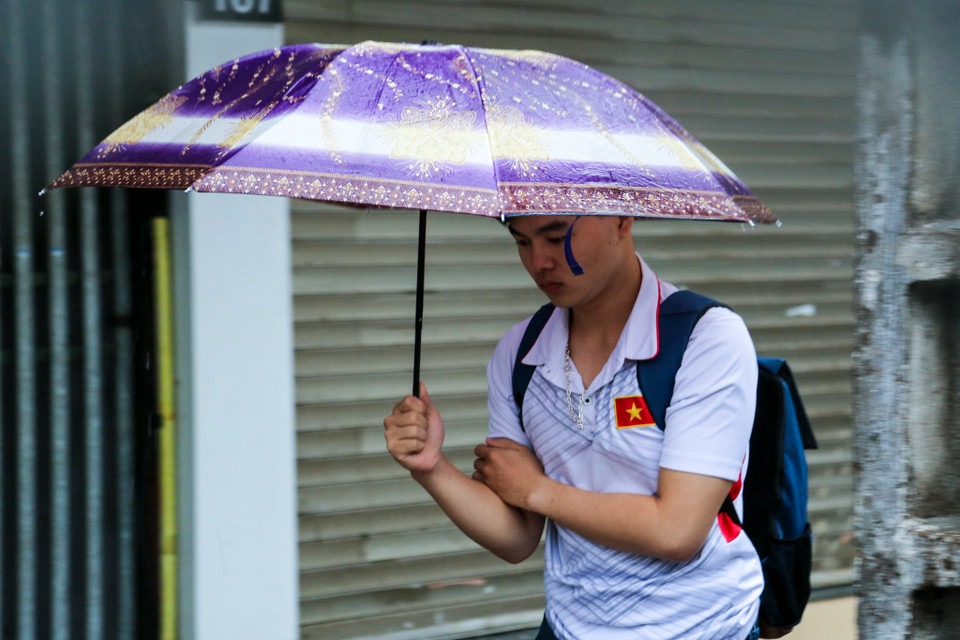 Nhiều người vẫn chủ quan mặc áo cộc ra đường đã phải co người lại vì không khí lạnh kèm theo mưa rào. (Ảnh: Minh Sơn/Vietnam+)