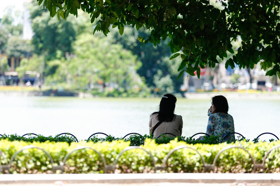 Hai bạn nữ tránh nắng trong một tán cây ở khu vực Bờ Hồ. (Ảnh: Minh Chiến/Vietnam+)