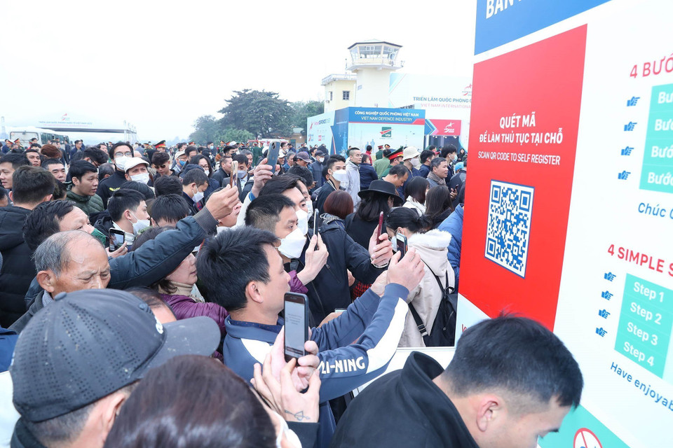 Du khách và nhân dân quyết mã QR trước khi vào tham quan triển lãm. (Ảnh: Trọng Đức/TTXVN)