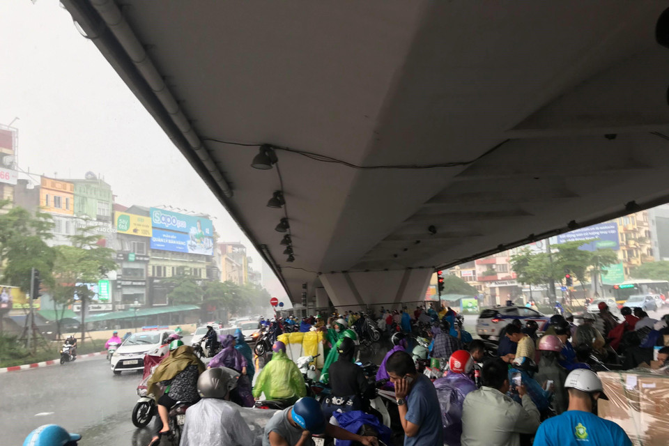 Mưa lớn khiến nhiều người phải trú mưa dưới chân cầu vượt ở Ngã Tư Sở làm tắc cả một đoạn đường Láng. (Ảnh: Trọng Đạt/TTXVN)