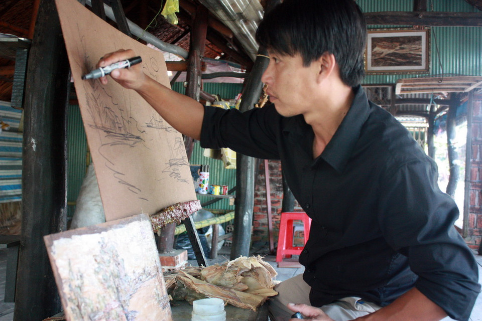 Anh Lê Hoàng Nhân phác họa bức tranh trước khi lắp ghép vỏ tràm. (Ảnh: Lê Sen/TTXVN)