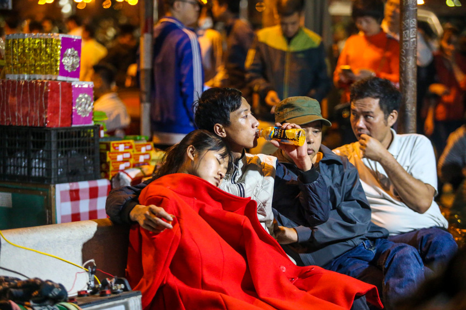 Phía bên ngoài rào sắt ngăn cách với khu vực sân đền, hàng trăm người cũng đã ngồi kín, mắt nhìn vào bên trong. Nhiều người do quá mệt mỏi nên tranh thủ ngủ gục. Mùi hương khói, mùi mồ hôi váng vất không ngăn cản được du khách háo hức đợi chờ. (Ảnh: PV/Vietnam+)