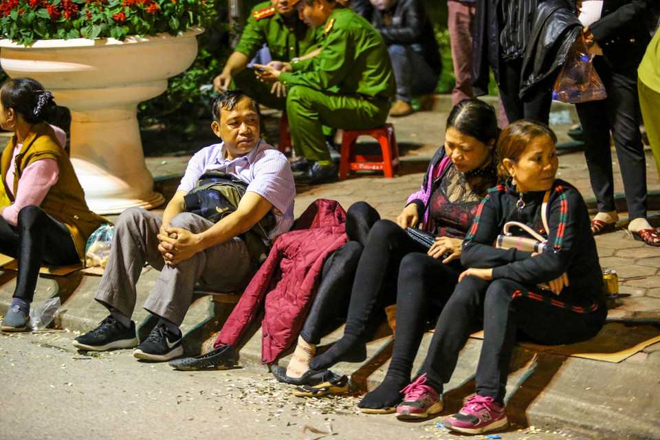 Có nhiều người vì quá mệt mỏi nên đã tranh thủ ngủ tạm ven đường, chờ tới giờ khai ấn để làm lễ. (Ảnh: PV/Vietnam+)