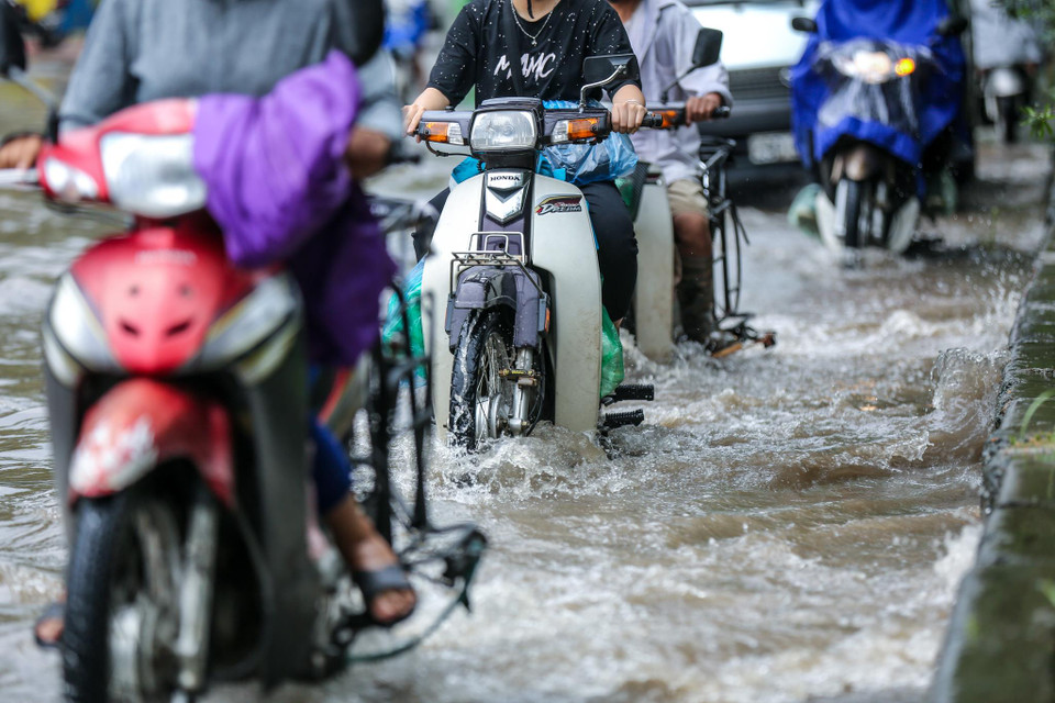 Nhiều phương tiện bất chấp nguy hiểm vẫn phóng xe qua khu vực ngập. (Ảnh: Minh Sơn/Vietnam+)