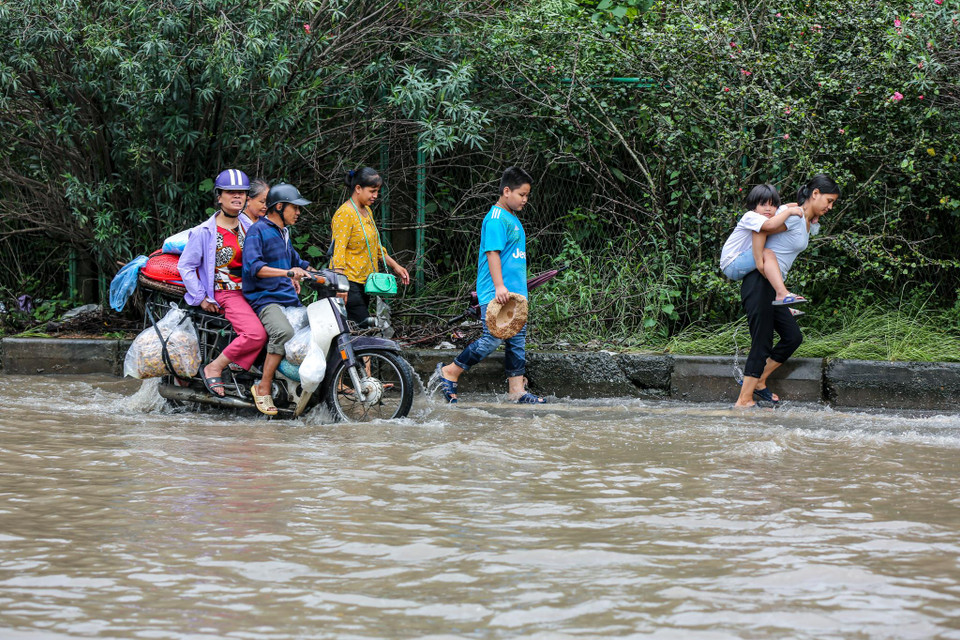Các gia đình bồng bế nhau đi qua khu vực ngập. (Ảnh: Minh Sơn/Vietnam+)