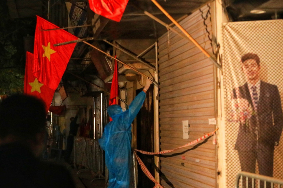 Lực lượng tình nguyện viên cắm cờ tổ quốc trước các nhà trên đường Nguyễn Trãi sau khi có quyết định dỡ bỏ phong tỏa ngõ 328, 330 đường Nguyễn Trãi. (Ảnh: Tuấn Anh/TTXVN)