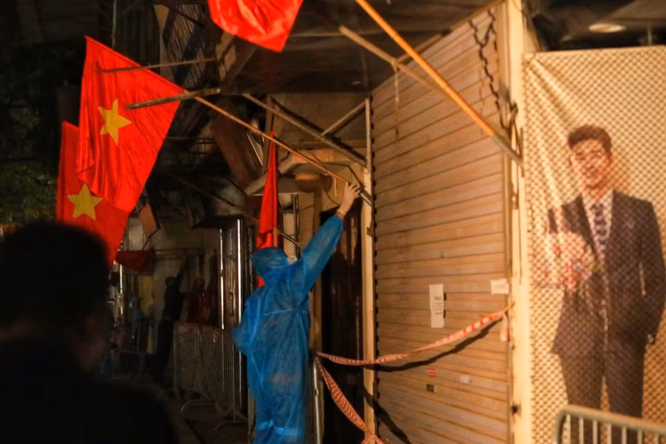 Lực lượng tình nguyện viên cắm cờ tổ quốc trước các nhà trên đường Nguyễn Trãi sau khi có quyết định dỡ bỏ phong tỏa ngõ 328, 330 đường Nguyễn Trãi. (Ảnh: Tuấn Anh/TTXVN)