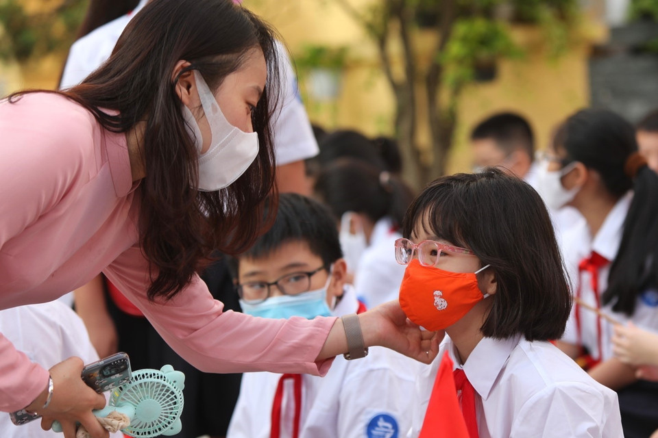 Cô giáo trường THCS Trưng Vương, quận Hoàn Kiếm (Hà Nội) chỉnh trang lại khẩu trang cho học sinh trong lễ khai giảng. (Ảnh: Danh Lam/TTXVN)