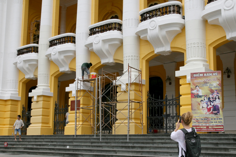 Du khách nước ngoài ghi lại hình ảnh Nhà hát Lớn Hà Nội trong quá trình chỉnh trang. (Ảnh: Lê Doãn Đức/Vietnam+)