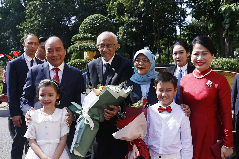 Chủ tịch nước Nguyễn Xuân Phúc và Phu nhân cùng Tổng thống Cộng hòa Singapore Halimah Yacob và Phu quân với thiếu nhi Thủ đô Hà Nội tại lễ đón. (Ảnh: Thống Nhất/TTXVN)