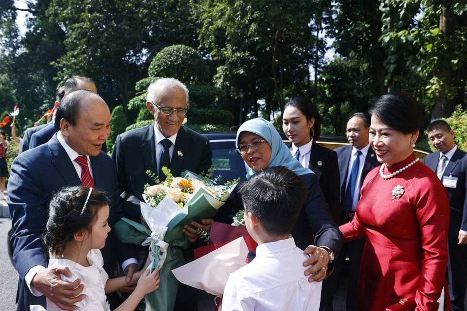 Chủ tịch nước Nguyễn Xuân Phúc và Tổng thống Cộng hòa Singapore Halimah Yacob với thiếu nhi Thủ đô Hà Nội tại lễ đón. (Ảnh: Thống Nhất/TTXVN)