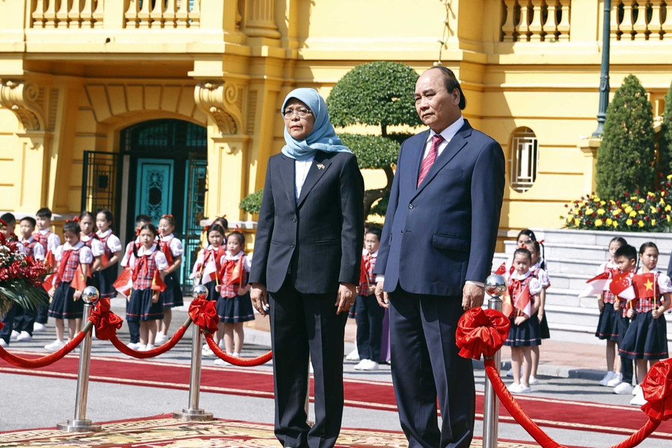 Chủ tịch nước Nguyễn Xuân Phúc và Tổng thống Cộng hòa Singapore Halimah Yacob nghe quân nhạc cử Quốc thiều hai nước. (Ảnh: Thống Nhất/TTXVN)