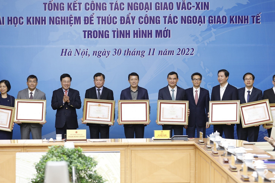 Phó Thủ tướng thường trực Phạm Bình Minh và Phó Thủ tướng Vũ Đức Đam trao Bằng khen của Thủ tướng cho các cá nhân có thành tích xuất sắc trong triển khai công tác ngoại giao vaccine. (Ảnh: Dương Giang/TTXVN)