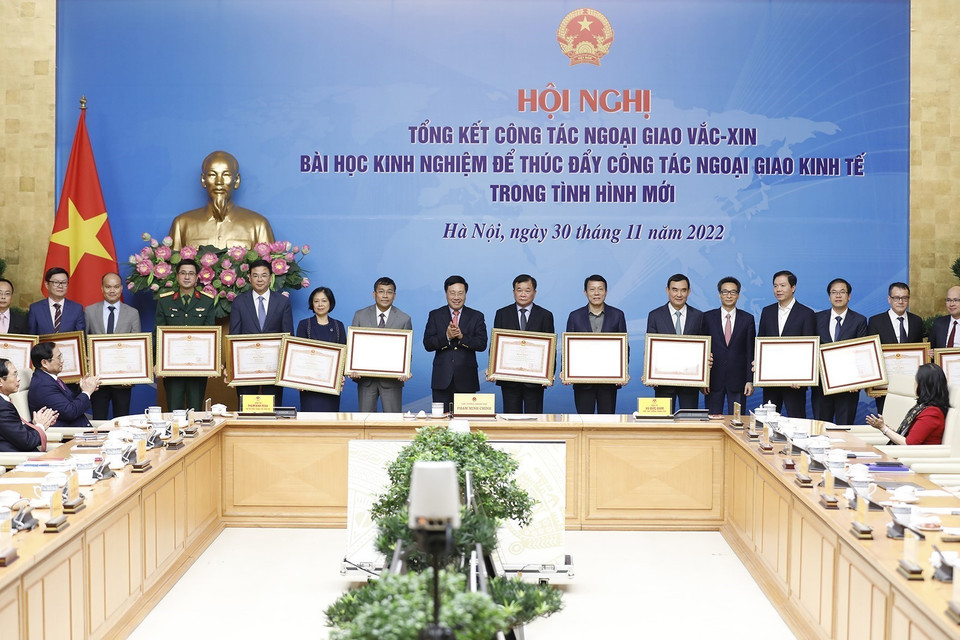 Phó Thủ tướng thường trực Phạm Bình Minh và Phó Thủ tướng Vũ Đức Đam trao Bằng khen của Thủ tướng cho các cá nhân có thành tích xuất sắc trong triển khai công tác ngoại giao vaccine. (Ảnh: Dương Giang/TTXVN)