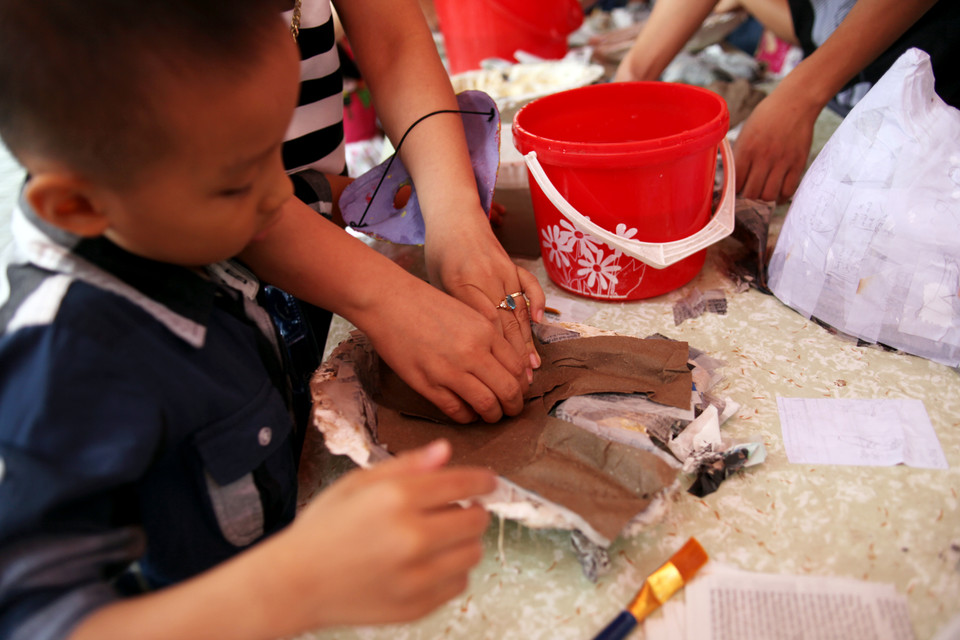 Bé Trung ở Thanh Xuân Bắc háo hức khi được tự tay bồi giấy. (Ảnh: Doãn Đức/Vietnam+)