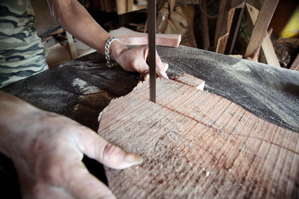 Sau đó, họ sẽ dùng cưa vanh cắt theo hình dáng khuôn bánh. (Ảnh: Doãn Đức/Vietnam+)