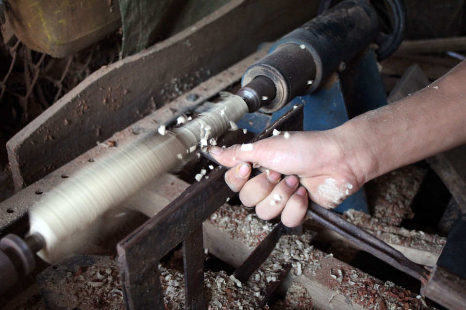 Phần cán cầm được tiện tròn để người thợ làm bánh cầm chắc tay. (Ảnh: Doãn Đức/Vietnam+)