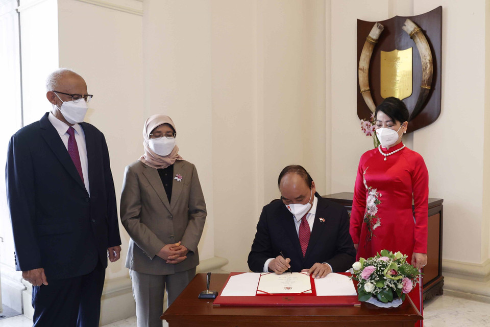 Chủ tịch nước Nguyễn Xuân Phúc ghi vào Sổ vàng lưu niệm tại Phủ Tổng thống Singapore. (Ảnh: Thống Nhất/TTXVN)