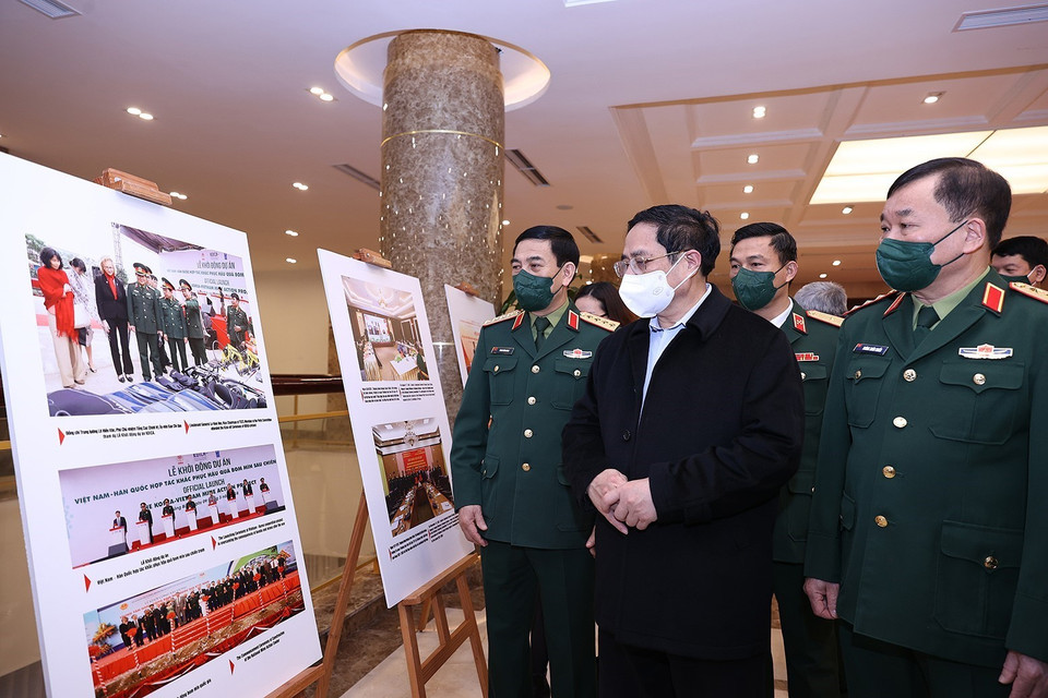 Thủ tướng Phạm Minh Chính tham quan trưng bày ảnh về phòng tránh bom mìn. (Ảnh: Dương Giang/TTXVN)