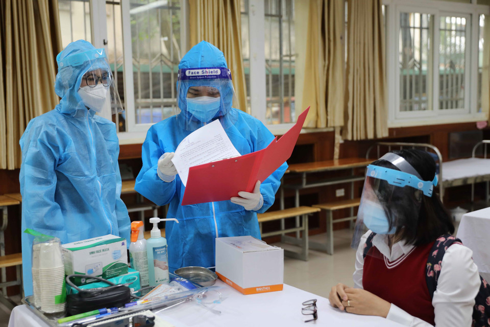 Nhân viên y tế phường xem hồ sơ của học sinh nghi mắc COVID-19. (Ảnh: Thanh Tùng/TTXVN)