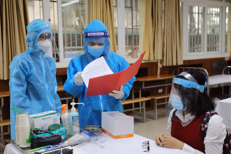 Nhân viên y tế phường xem hồ sơ của học sinh nghi mắc COVID-19. (Ảnh: Thanh Tùng/TTXVN)