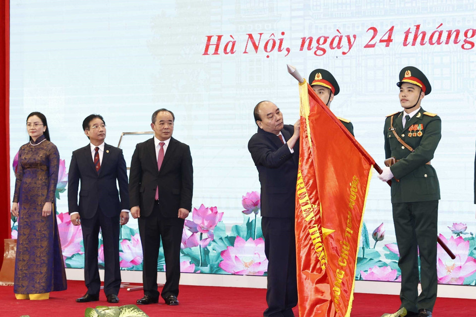 Chủ tịch nước Nguyễn Xuân Phúc gắn Huân chương Lao động hạng Nhất lên lá cờ truyền thống của Văn phòng Chủ tịch nước. (Ảnh: Trí Dũng/TTXVN)