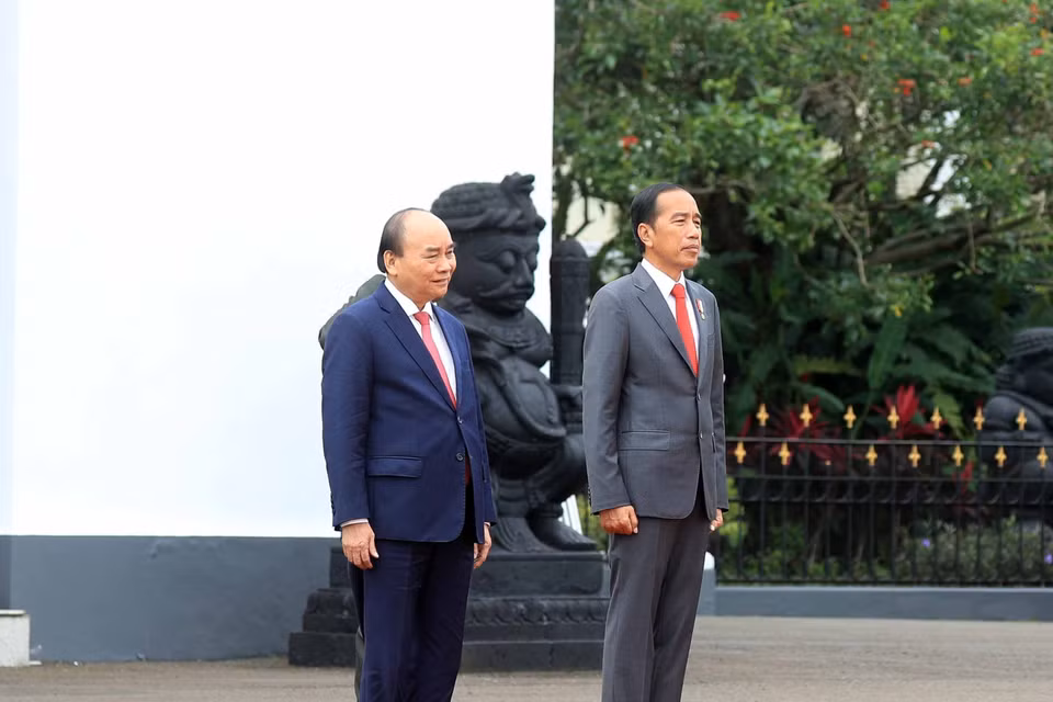 Chủ tịch nước Nguyễn Xuân Phúc và Tổng thống nước Cộng hòa Indonesia Joko Widodo nghe quân nhạc cử Quốc thiều hai nước. (Ảnh: Thống Nhất/TTXVN)