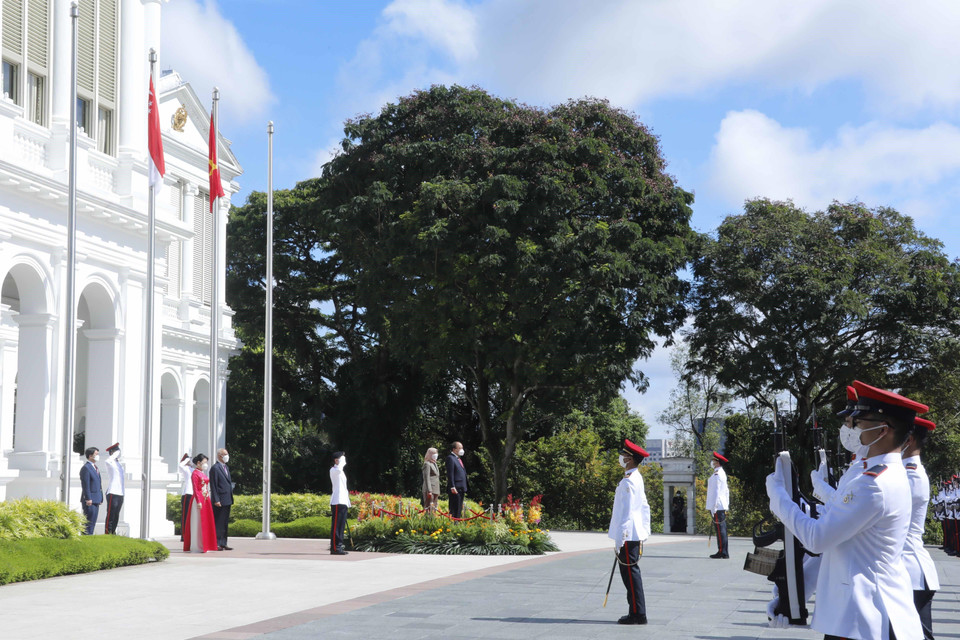 Chủ tịch nước Nguyễn Xuân Phúc và Tổng thống Cộng hòa Singapore Halimah Yacob nghe quân nhạc cử Quốc thiều hai nước. (Ảnh: Thống Nhất/TTXVN)