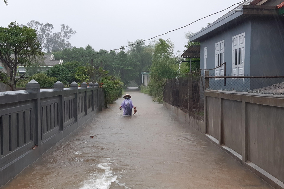 Người dân lội nước lụt tại thôn Xuân Tùy (xã Quảng Phú, huyện Quảng Điền). (Ảnh: Mai Trang/TTXVN)