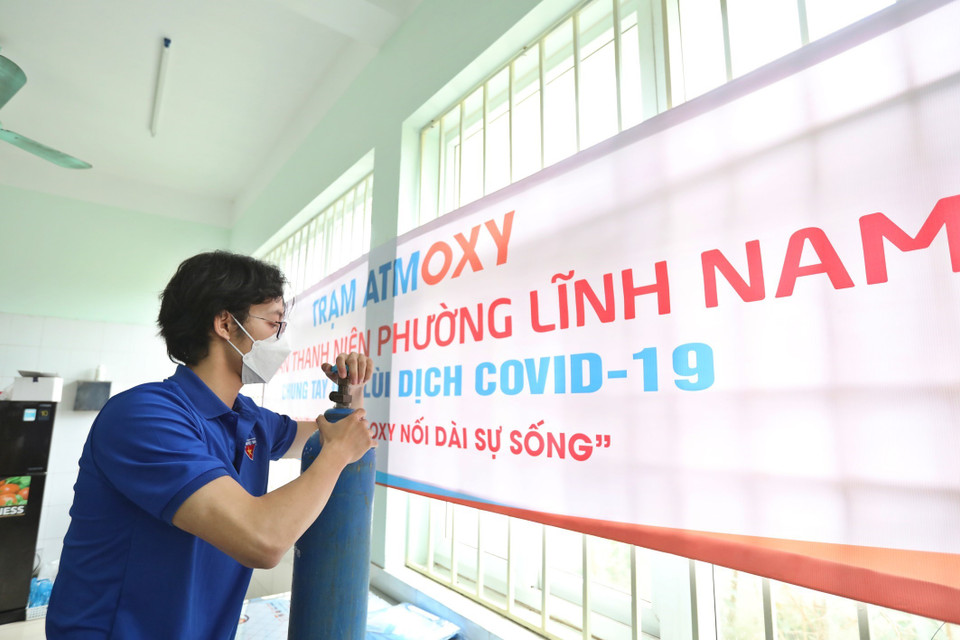 Thành viên Tổ hỗ trợ theo dõi người nhiễm COVID-19 tại nhà phường Lĩnh Nam kiểm tra bình oxy trước khi mang đến hỗ trợ F0 cách ly y tế, điều trị tại nhà. (Ảnh: Minh Quyết/TTXVN)