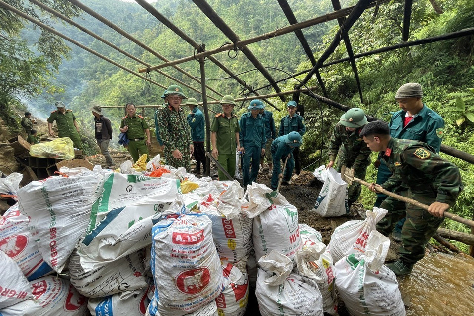 Các lực lượng tại bãi vàng Nậm Suổng tiến hành xúc đất vào bao tải để vận chuyển vào hầm che đậy vật liệu nổ tạo độ nén và sức công phá lớn. (Ảnh: Việt Hoàng/TTXVN)