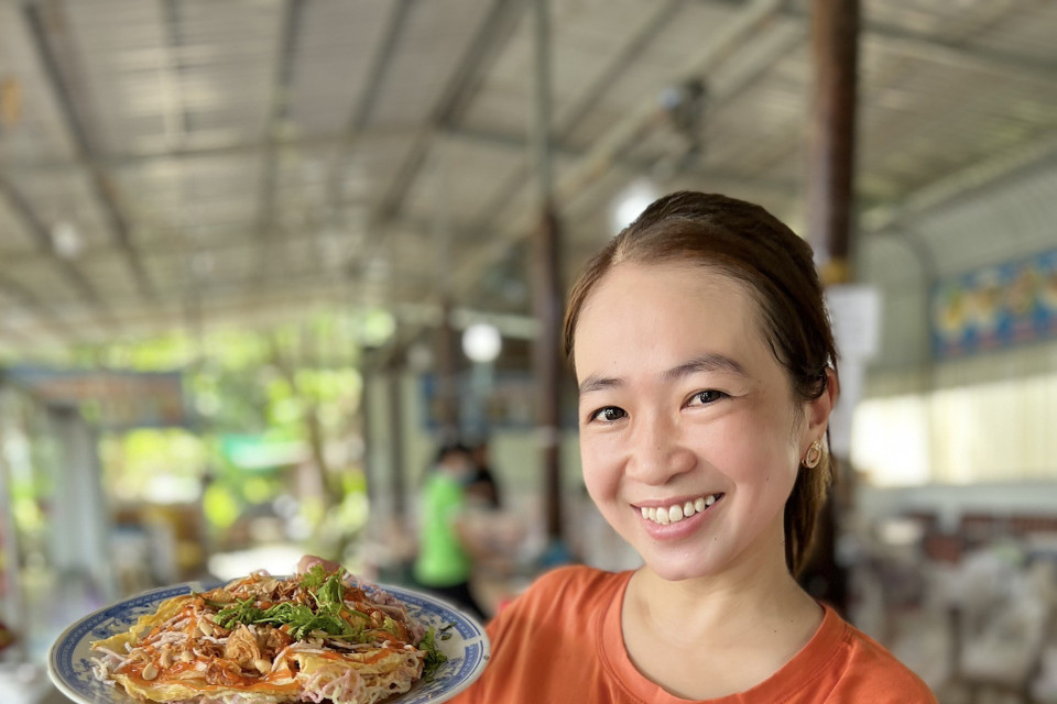 Du khách với món pizza hủ tiếu độc quyền của lò hủ tiếu Sáu Hoài. (Ảnh: TTXVN phát)