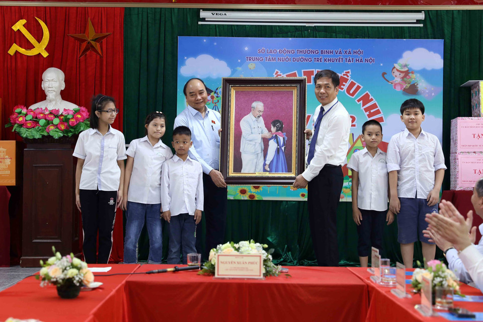 Chủ tịch nước Nguyễn Xuân Phúc tặng bức tranh Chủ tịch Hồ Chí Minh với thiếu nhi cho Trung tâm Nuôi dưỡng trẻ khuyết tật Hà Nội. (Ảnh An Đăng/TTXVN)