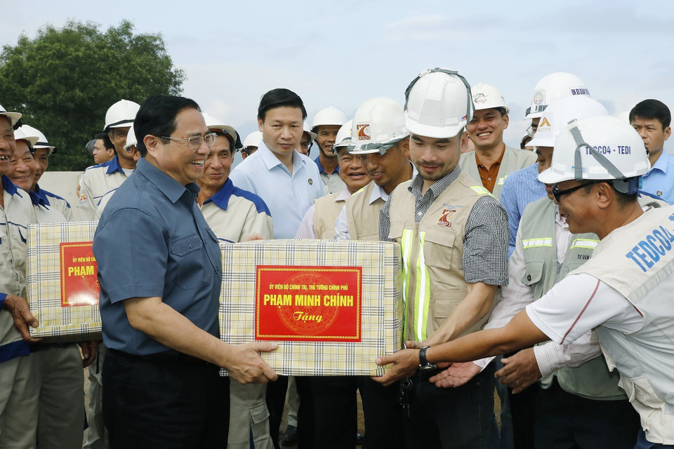 Thủ tướng Phạm Minh Chính tặng quà cho công nhân đang xây dựng dự án tuyến đường Đông-Tây giai đoạn 1. (Ảnh: Dương Giang/TTXVN)