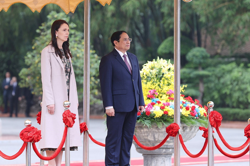 Thủ tướng Phạm Minh Chính và Thủ tướng New Zealand Jacinda Ardern nghe quân nhạc cử Quốc thiều hai nước. (Ảnh: Dương Giang/TTXVN)