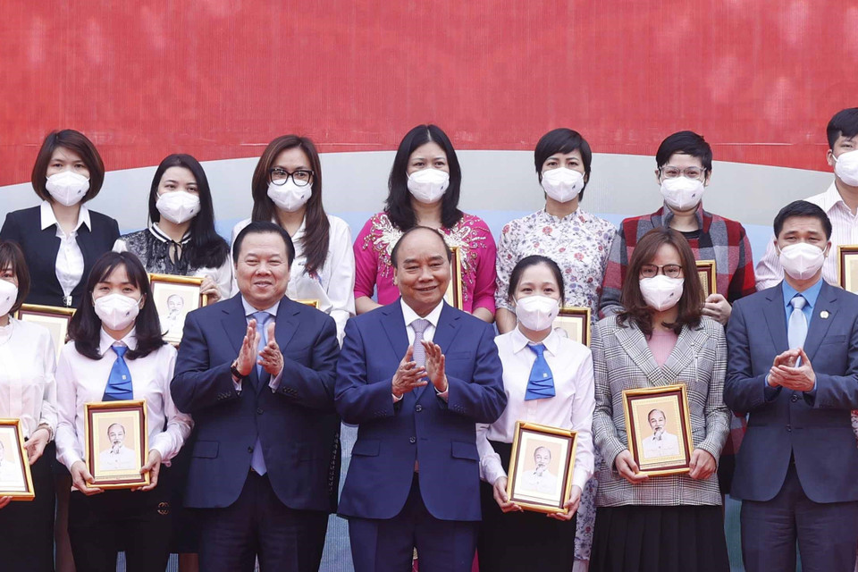 Hình ảnh Chủ tịch nước Nguyễn Xuân Phúc tặng ảnh chân dung Chủ tịch Hồ Chí Minh cho các cá nhân có thành tích xuất sắc của Tập đoàn Dệt may Việt Nam. (Ảnh: Thống Nhất/TTXVN)