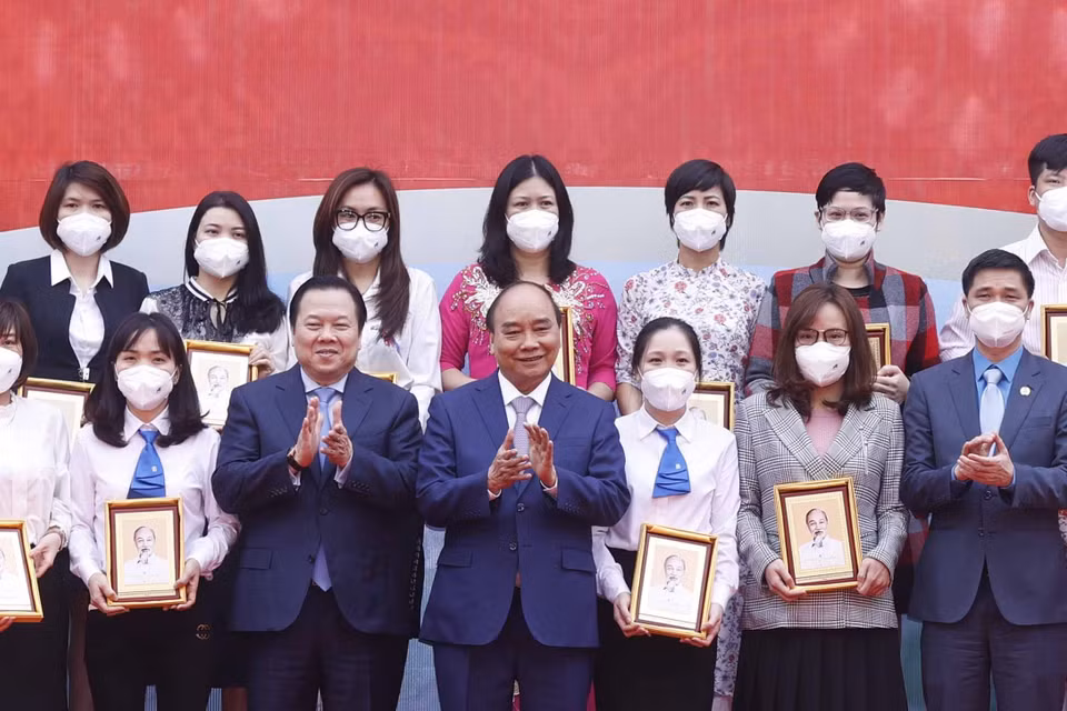 Hình ảnh Chủ tịch nước Nguyễn Xuân Phúc tặng ảnh chân dung Chủ tịch Hồ Chí Minh cho các cá nhân có thành tích xuất sắc của Tập đoàn Dệt may Việt Nam. (Ảnh: Thống Nhất/TTXVN)