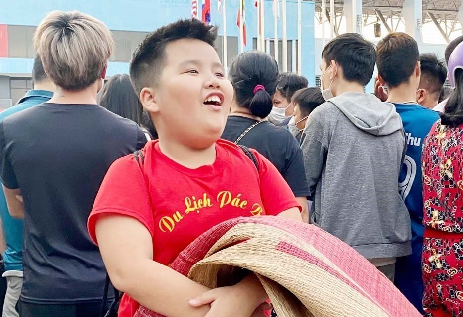 Cổ động viên nhí hào hứng mang chiếu đợi sẵn để nhận vé mời xem trận chung kết. (Ảnh: Thanh Vân/TTXVN)