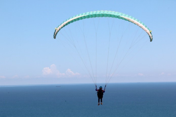 Khi chơi trò dù lượn mạo hiểm, du khách sẽ được ngắm nhìn cảnh núi và biển tuyệt vời từ trên cao. (Ảnh: Nguyễn Thanh/TTXVN)
