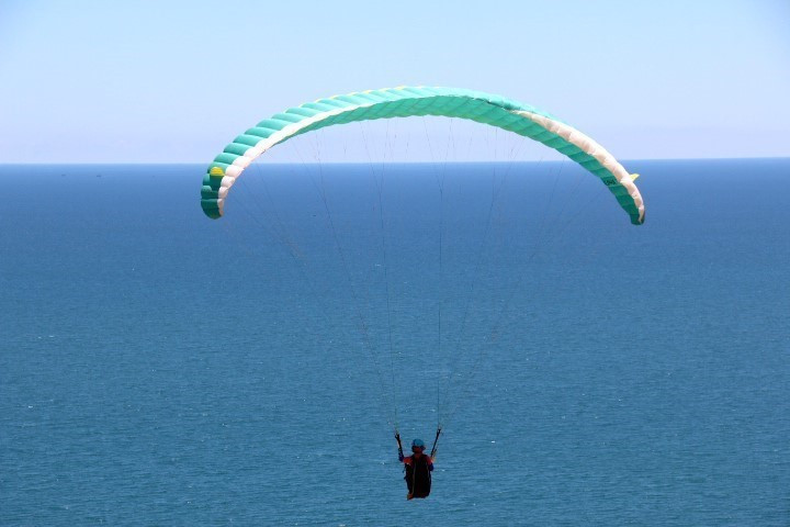 Khi chơi trò dù lượn mạo hiểm, du khách sẽ được ngắm nhìn cảnh núi và biển tuyệt vời từ trên cao. (Ảnh: Nguyễn Thanh/TTXVN)