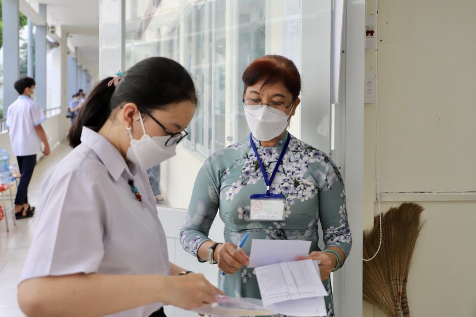 Các thí sinh tại điểm thi trường Trung học phổ thông Bùi Thị Xuân (Quận 1) được giám thị kiểm tra thông tin cá nhân trước khi vào phòng thi. (Ảnh: Hồng Giang/TTXVN)