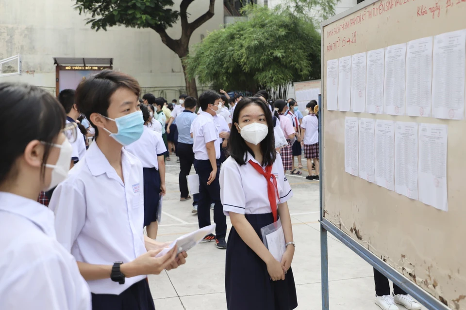 Các thí sinh kiểm tra, rà soát lại tên và số báo danh dự thi tại điểm thi trường Trung học phổ thông Bùi Thị Xuân (Quận 1). (Ảnh: Hồng Giang/TTXVN)